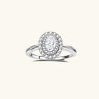 Sterling silver ring with oval moissanite center stone surrounded by double halo of sparkling stones on neutral background.
