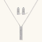 White gold plated necklace with vertical cubic zirconia pendant and matching hoop earrings on neutral background