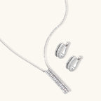 White gold plated necklace with vertical cubic zirconia pendant and matching hoop earrings on neutral background