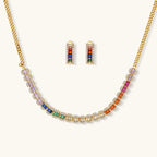 Gold-plated jewelry set featuring rainbow baguette-cut cubic zirconia stones in geometric design on cream background