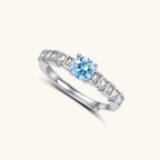 Geometric sterling silver ring with light blue moissanite center stone and square diamond accents on white background