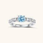 Geometric sterling silver ring with light blue moissanite center stone and square diamond accents on white background