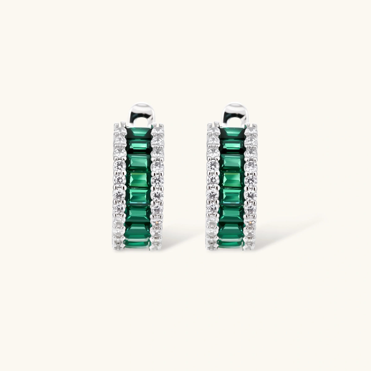 White gold plated jewelry set with emerald green rectangular stones and clear crystals in geometric rows on white background.