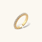 Close-up of adjustable gold-plated ring with continuous row of round zirconia stones on neutral background.