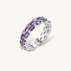 Close-up of adjustable ring with oval purple zirconia stones in white gold-plated copper setting on neutral background.