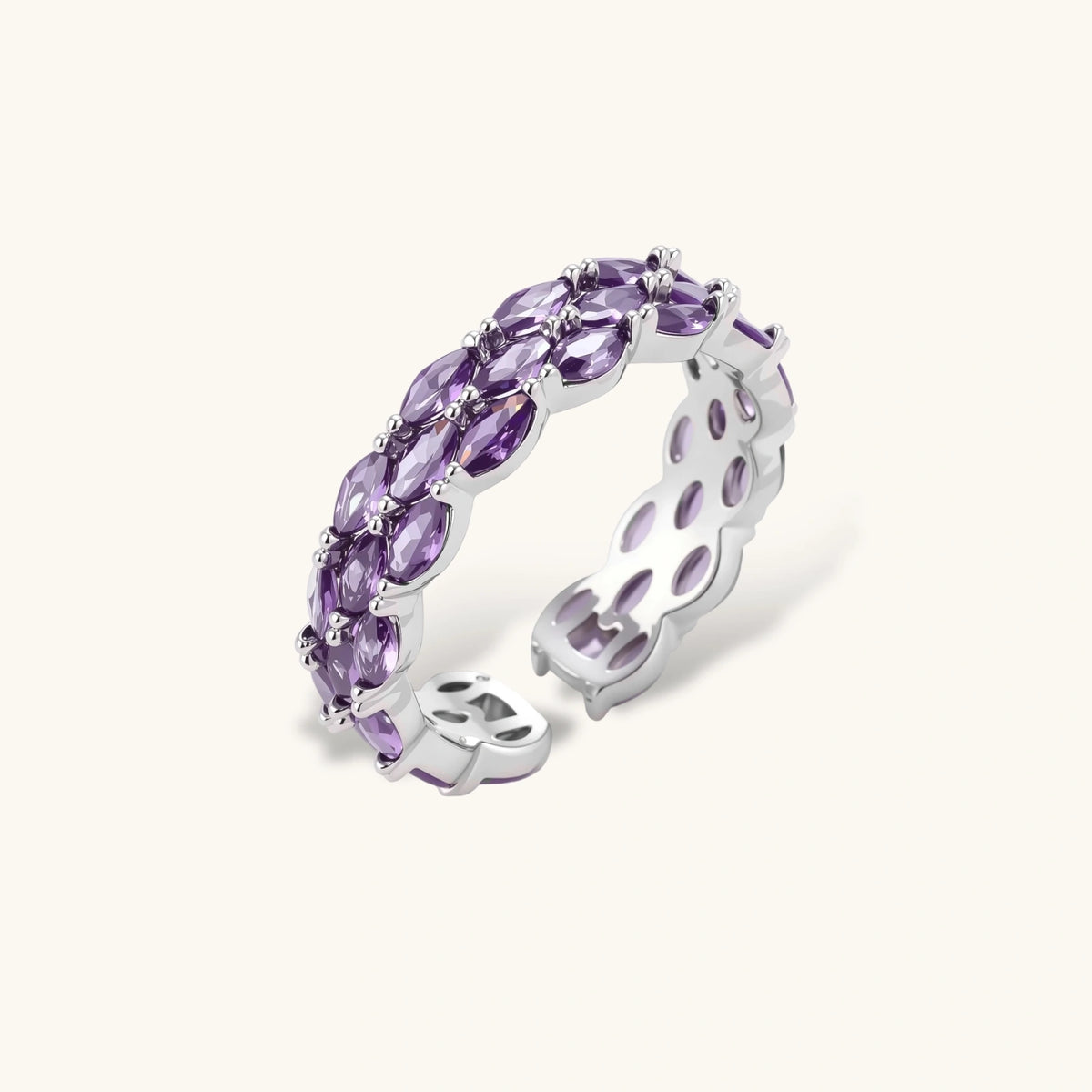 Close-up of adjustable ring with oval purple zirconia stones in white gold-plated copper setting on neutral background.
