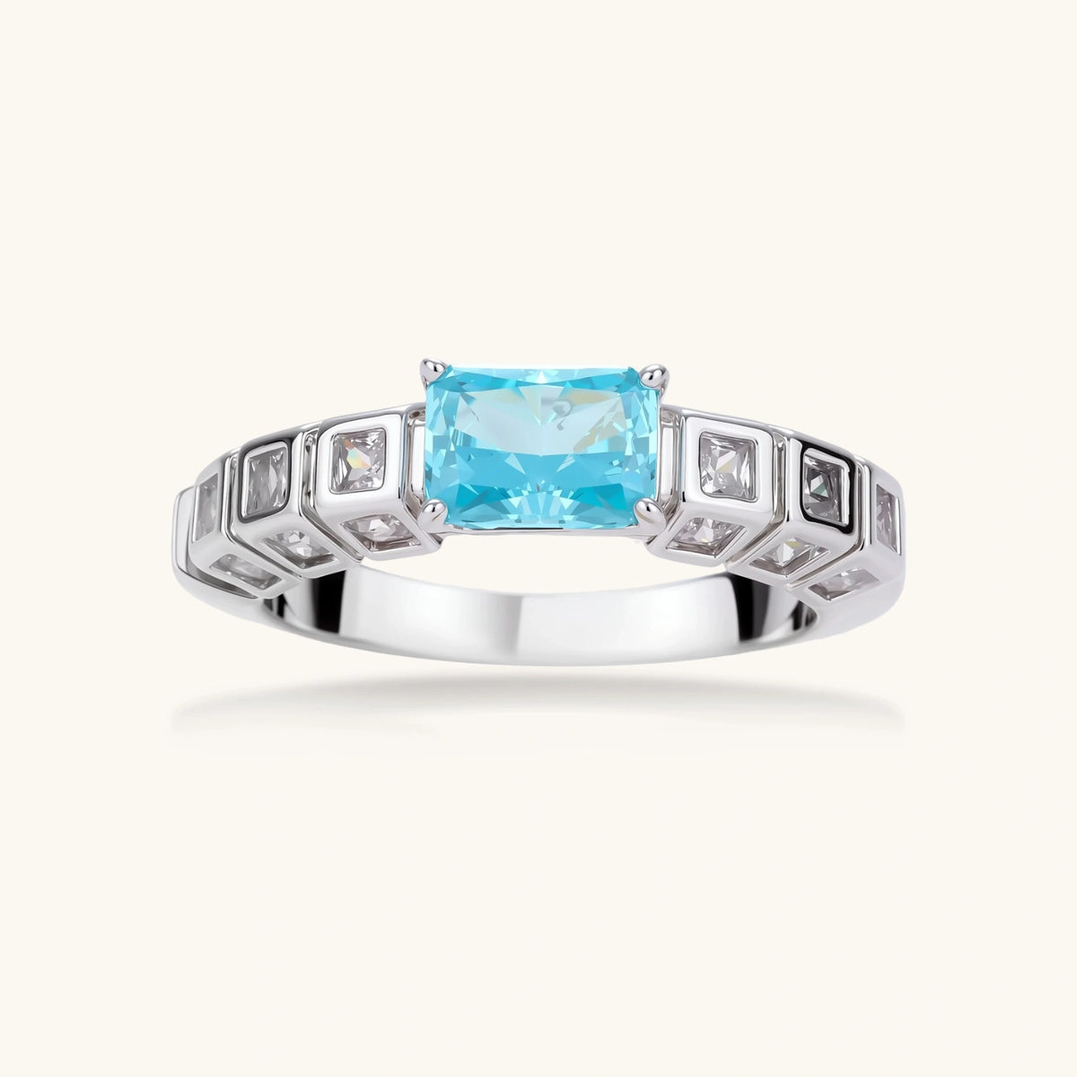Geometric silver-plated ring with rectangular aqua cubic zirconia center and square crystal details on adjustable band.